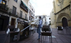 Un trabajador recoge el mobiliario de la terraza de un restaurante en el centro de Córdoba.