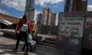 Varias personas caminan frente a un grafiti que dice "La maternidad será deseada o no será aborto legal" en una pared, el 16 de enero de 2021, en Caracas (Venezuela). Una niña de 13 años que era abusada sexualmente por un vecino interrumpió, de manera vo