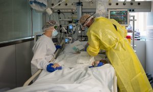 Dos sanitaris visitant un pacient de Covid a l'UCI de l'Hospital Clínic protegits amb EPI.