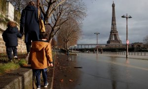 Una mujer pasea con sus hijos bordeando el río Sena por su crecida con la torre Eiffel de fondo en París.