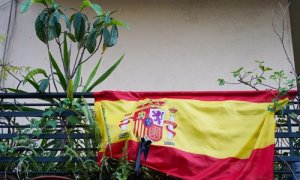 Banderas de España con crespones negros en un balcón.