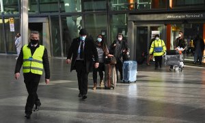 Viajeros internacionales son escoltados a su llegada al aeropuerto londinense de Heathrow hasta el Radison Blu Hotel, donde tienen que hacer cuarentena.