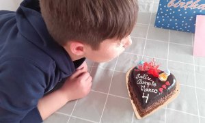 Marco, con 9 años, sopla la vela de la tarta con la celebra con su familia los 4 años como Marco.