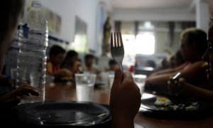 Un grupo de niños comen en en un comedor.