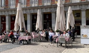Varios turistas en su mayoría franceses disfrutan del sol en la Plaza Mayor de Madrid.