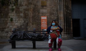 Una dona sense sostre menja en zones exteriors de les instal·lacions de l'Hospital de Campanya de la parròquia de Santa Anna.