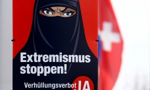 12/02/2021. Una bandera nacional suiza ondea detrás de un cartel que dice "¡Alto al extremismo! Prohibición del velo, Sí" en Berikon, Suiza. - Reuters