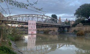 Tres hombres despliegan un cartel en el Puente Nuevo, en Murcia, asegurando: "Soy mujer y no me representan"