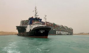 Un barco vigila el buque portacontenedores que fue golpeado por un fuerte viento y encalló en el Canal de Suez, Egipto.