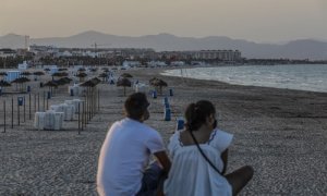 Dos jóvenes sentados contemplan la playa de la Malvarrosa durante la noche de San Juan en Valencia, Comunidad Valenciana (España), a 23 de junio de 2020.