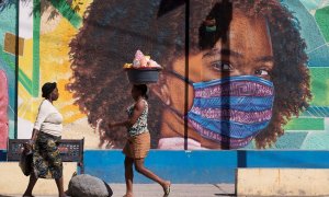 Dos mujeres caminan frente a un mural alusivo al uso del tapabocas por el coronavirus en Puerto Príncipe (Haití).