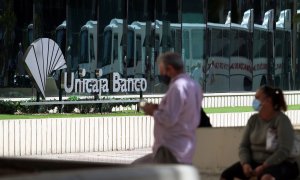 Dos personas en las inmediaciones de la sede de Unicaja Banco en Málaga. E.P./Álex Zea