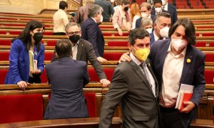 Pla conjunt dels negociadors d'ERC i Joan Candell i Francesc de Dalmases (JxCat) passant pel costat a l'hemicicle del Parlament el 13 d'abril del 2021.