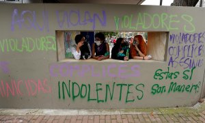 Varias mujeres conversan frente a una pared con grafitis pintados en las paredes de un Comando de Atención Inmediata (CAI) de la Policía durante unas protestas en Bogotá (Colombia).