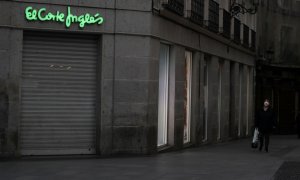 Una mujer con mascarilla pasa por delante de una tienda de El Corte Inglés en el centro de Madrid, cerrada durante el confinamiento decretado en marzo de 2020 por la pandemia del coronavirus. REUTERS/Susana Vera