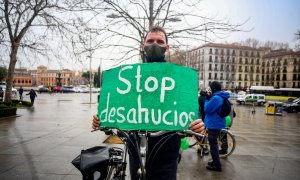 Un hombre con un cartel en el que se lee: `Stop desahucios´ en el final de la bicicletada durante una manifestación por el derecho a la Vivienda en Atocha, Madrid (España), a 21 de febrero de 2021.