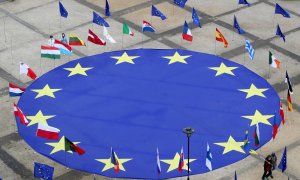 Una enorme bandera de la Unión Europea, rodeada junto a otras de los diferentes países comunitarios, aparece desplegada en la Plaza Schuman, frente a la sede de la Comisión Europea, en Bruselas, con motivo del Día de Europa. REUTERS/Yves Herman