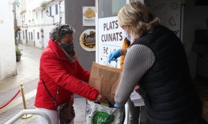 Una dona en situació vulnerable recollint menjar.