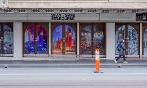 Una mujer pasa junto a un letrero de 'Stay Safe Melbourne' en una calle del centro de la ciudad.