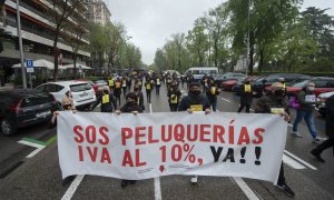 Un grupo de personas sostiene una pancarta donde se puede leer "SOS Peluquerías IVA al 10% ya!" en una concentración del sector de la imagen, a 26 de abril de 2021