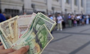 Una persona muestra varios billetes de las antiguas pesetas mientras espera cola a las puertas del Banco de España donde procederá a canjearlas el 25 de junio de 2021.