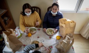Dos mujeres y un niño durante la comida en su casa del barrio madrileño de Carabanchel prueban el menú de la ONG del chef José Andrés.