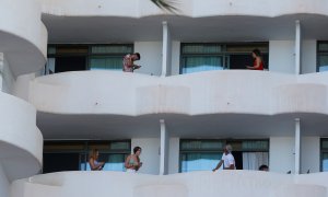 Varios de los jóvenes que permanecen en aislamiento en el hotel Palma Bellver de Palma, en los balcones de sus habitaciones.  REUTERS/Enrique Calvo