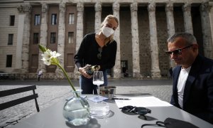 Una camarera sirve a un cliente en un restaurante en Roma.