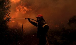 El bombero Nektarios Iakovakis lucha contra las llamas durante un incendio forestal en la aldea de Pefki en Evia, Grecia.