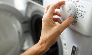 Una persona manipula una lavadora en plena escalada de los precios de la luz.