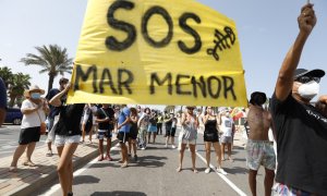 Varias personas participan en una protesta en defensa del Mar Menor al paso de la Vuelta Ciclista a España, a 21 de agosto de 2021, en La Manga.