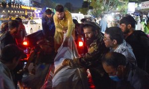 Voluntarios y personal médico descargan de una camioneta frente a un hospital el cuerpo de uno de los fallecidos en los atentados en Kabul. AFP/Wakil KOHSAR