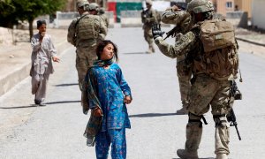 Unos niños pasan al lado de soldados estadounidenses en Afganistan.