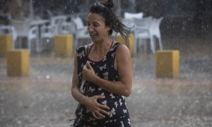 Una mujer corre bajo la lluvia en la Alameda de Hércules (Sevilla) a 14 de septiembre de 2021.