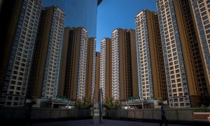 Una mujer camina cerca de bloques de edificios de apartamentos levantados por la inmobiliaria Evergrande, en Pekín. EFE/ROMAN PILIPEY