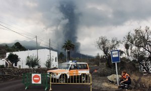 Un trabajador de Protección Civil fuma un cigarrillo mientras hace guardia para impedir el paso de vehículos y transeúntes en una carretera que lleva El Paraíso, evacuado por la cercanía del volcán.