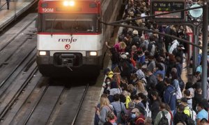 Un gran número de pasajeros espera la llegada de un tren en la estación de Madrid.