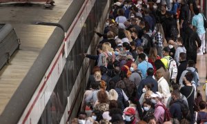 Un gran número de pasajeros espera la llegada de un tren en la estación de Madrid.