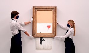 Empleados de la galería posan para los fotógrafos junto a la obra autodestruida de Banksy en la casa de subastas Sotheby's en Londres, Gran Bretaña, 03 de septiembre de 2021.