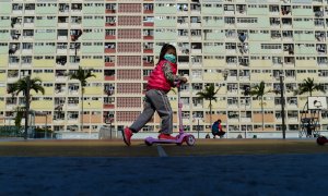 Una niña con una mascarilla protectora juega en los terrenos de una urbanización en el distrito de Kowloon en Hong Kong, a 31 de enero de 2020.