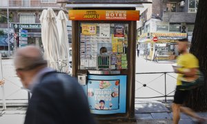 Dos personas pasan junto al quiosco de la ONCE, en Madrid. E.P./Jesús Hellín