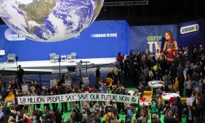 Un grupo de personas realiza una protesta en la COP26 con una pancarta que reza: "1,8 millones de personas dicen: salvad nuestro futuro ahora".