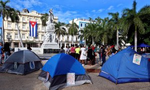 Jóvenes oficialistas instalan hoy carpas durante una sentada con pañuelos rojos en apoyo al Gobierno en el Parque Central de La Habana.