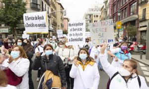 Una mujer sostiene una pancarta que exige "Municipalizar el Servicio de la Ayuda a Domicilio", en una manifestación de profesionales sociosanitarias.