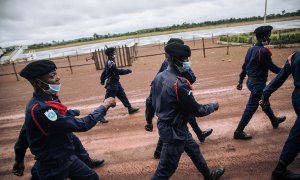 Agentes de la Policía congoleña desfilan en la pista del aeropuerto de Gbadolite, en el norte de la República Democrática del Congo, para la repatriación de refugiados centroafricanos a Bangui, el 15 de noviembre de 2021.