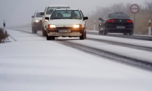 Vehículos circulan con dificultad por la carretera CL-505 en Ávila por la nieve este 8 de diciembre de 2021.