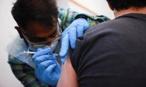 Un hombre administra una dosis de la vacuna contra la covid a una persona en un centro de vacunación de Londres, Gran Bretaña, el 15 de diciembre de 2021.