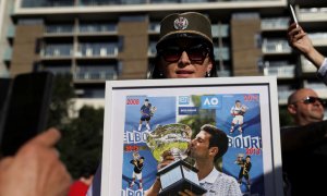 Una mujer sostiene un montaje con las victorias de Djokovic en el Open de Australia a las afueras del tribunal que ha decidido dejarle en libertad en Melbourne este lunes 10 de enero de 2022.