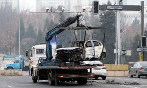 Una grúa carga un automóvil, quemado durante los enfrentamientos, en Almaty el 10 de enero de 2022, tras las protestas por el aumento de precio del combustible.