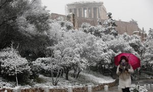 Una mujer con un paraguas pasea por la zona del Partenón, cubierto bajo un manto de nieve en Atenas (Grecia) este lunes 24 de enero de 2022.